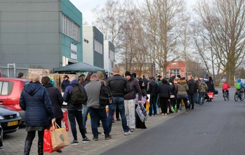 Een lange wachtrij met mensen die in de rij staan voor de voedselbank.