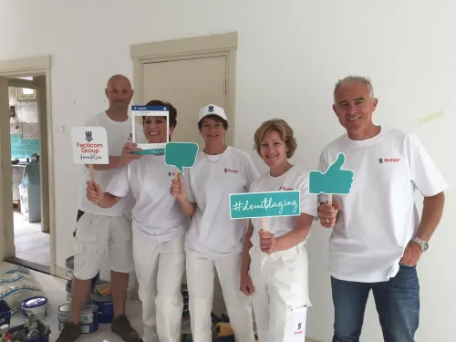 Groepsfoto van Facilicom-medewerkers die vrijwilligerswerk doen bij het babyhuis.