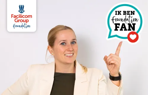 een dame wijst schuin naar boven naar het embleem van 'Ik ben Foundation Fan'