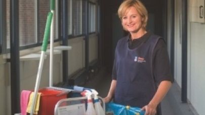Schoonmaakster aan het werk met naast haar haar werkkar Schoonmaakster aan het werk met naast haar haar werkkar