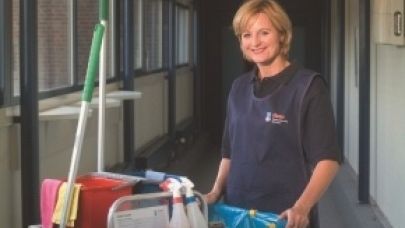 Schoonmaakster aan het werk met naast haar haar werkkar