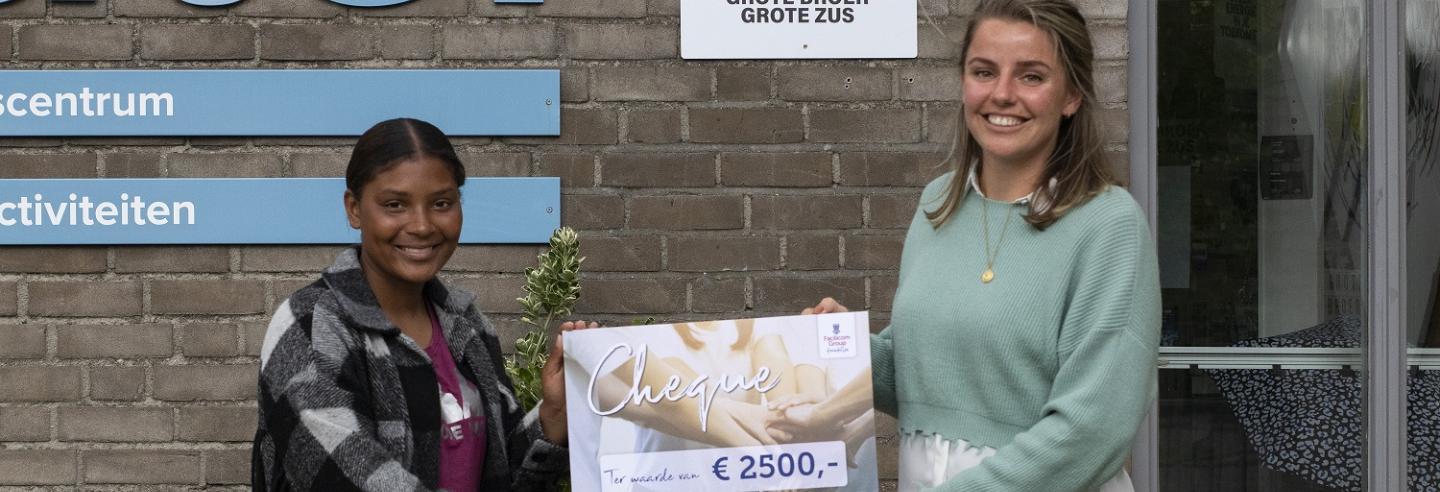 Diede Smit overhandigt een cheque ter waarde van 2500 euro aan een vrijwilligster van Stichting Grote Broer