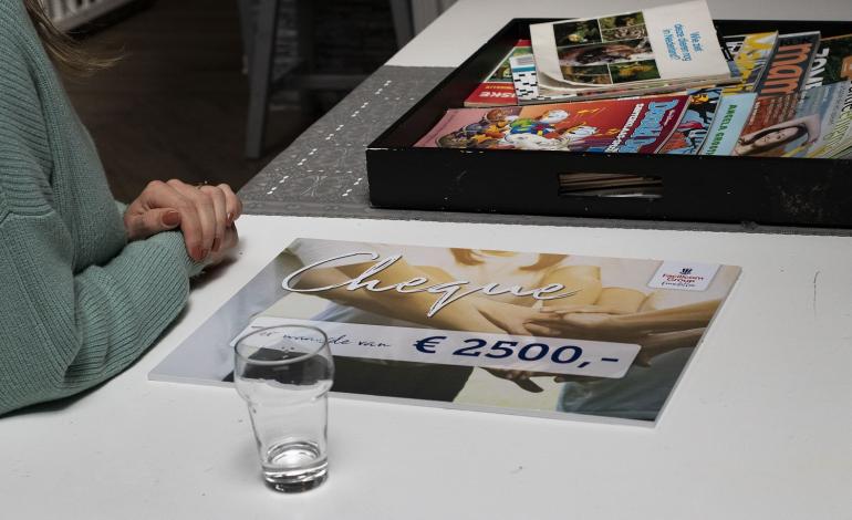Een cheque van Facilicom Foundation ter waarde van 2500 ligt op tafel.