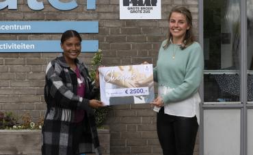 Diede Smit overhandigt een cheque ter waarde van 2500 euro aan een vrijwilligster van Stichting Grote Broer