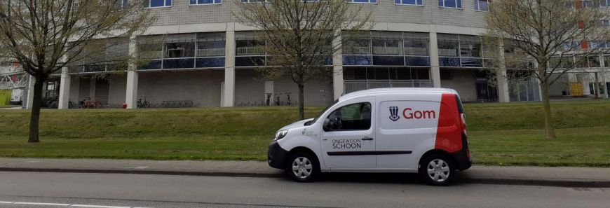 Kleine elektrische bestelauto voor gebouw en grasveld