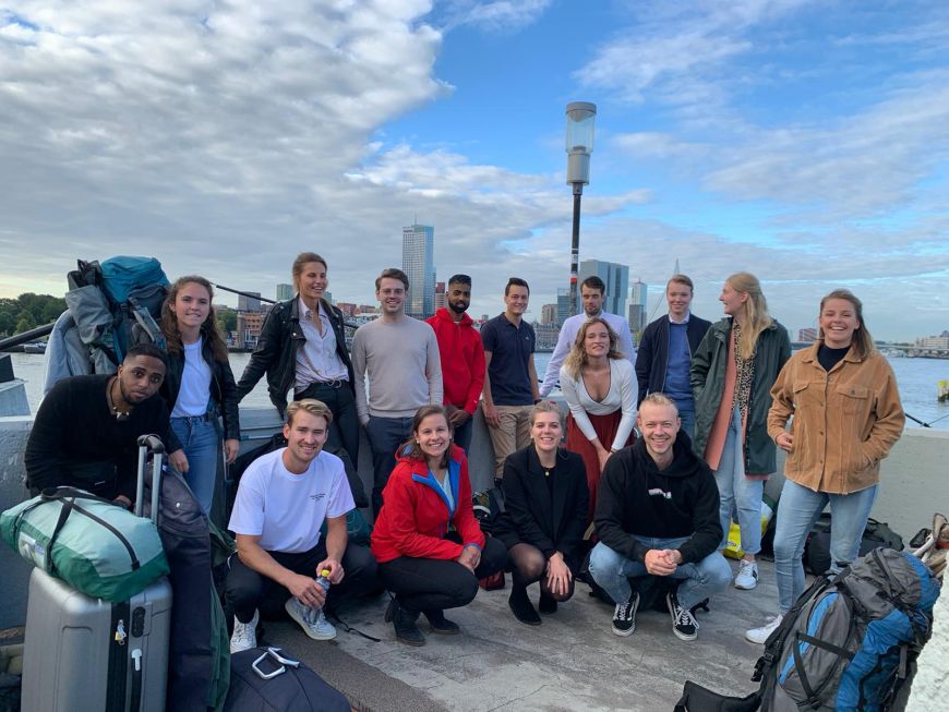 Groepsfoto van de Facilicom Group trainees op een schip met de skyline van Rotterdam op de achtergrond.