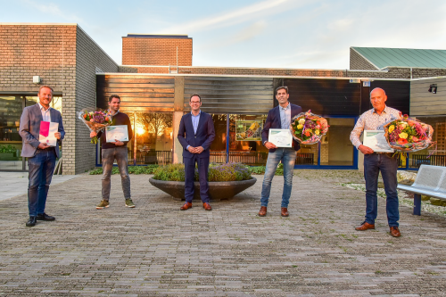 Foto van viertal heren die keurmerk in ontvangst nemen staand op een pleintje