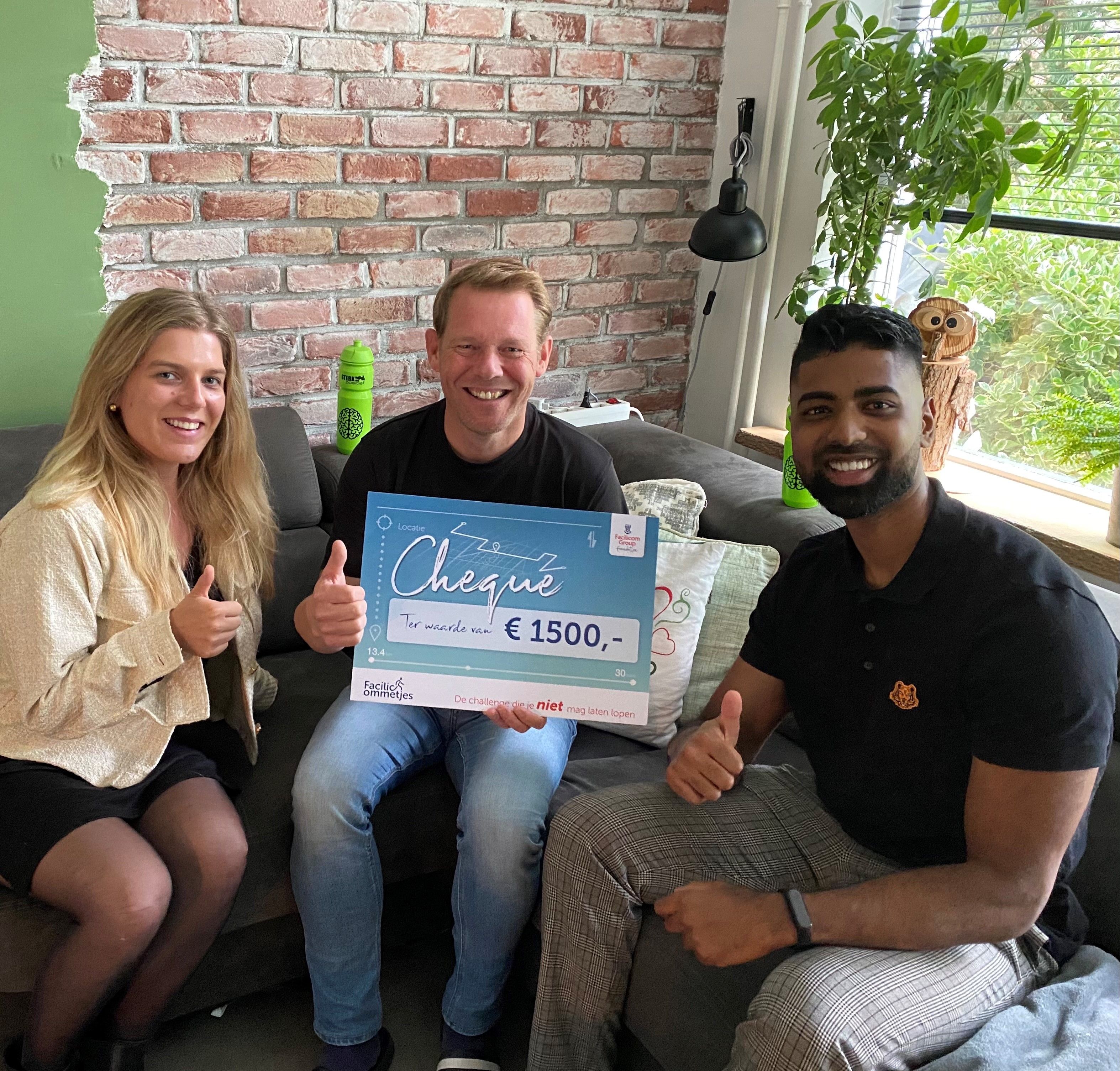 Twee management trainees van Facilicom reiken een cheque van 1500 euro uit aan de contactpersoon van Stichting Sterk en Positief.